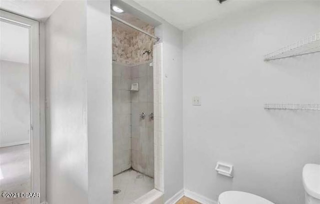 bathroom with toilet and a tile shower