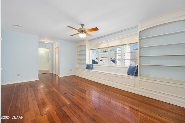 empty room with hardwood / wood-style floors, built in features, and ceiling fan