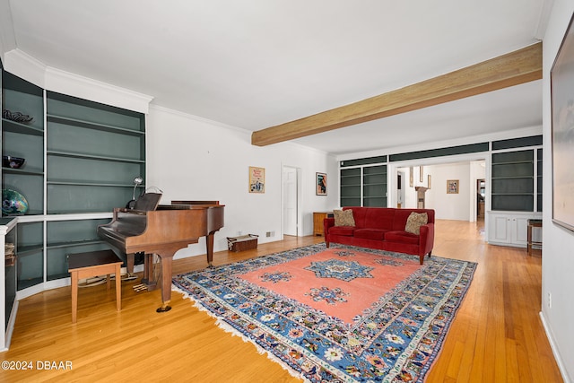 living room with built in features, wood-type flooring, crown molding, and beam ceiling