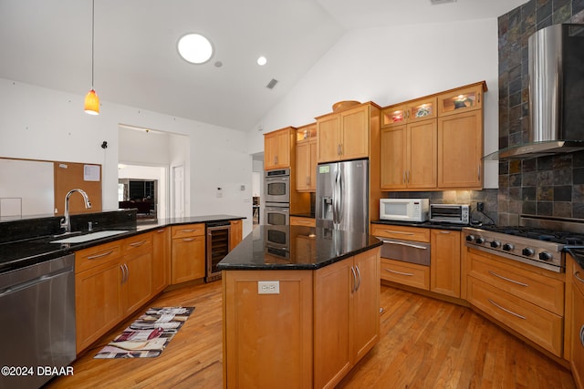 kitchen with stainless steel appliances, a center island, beverage cooler, wall chimney exhaust hood, and light wood-type flooring