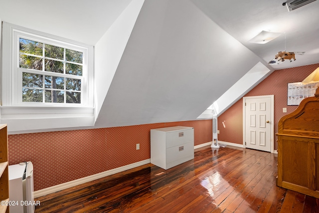 bonus room with dark wood-type flooring and vaulted ceiling with skylight