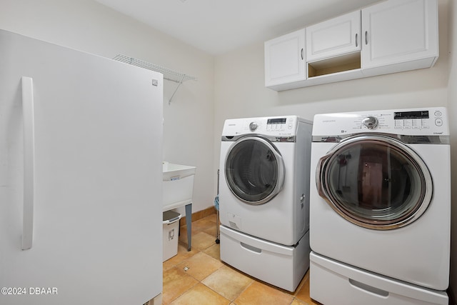 laundry area with cabinets, light tile patterned floors, and independent washer and dryer