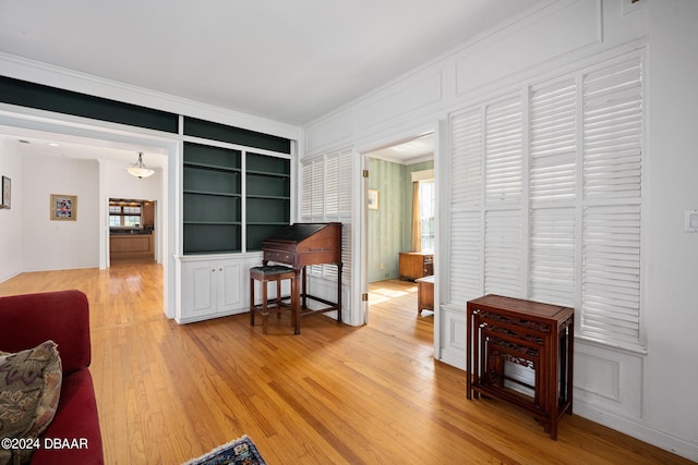 interior space with wood-type flooring, built in shelves, and ornamental molding