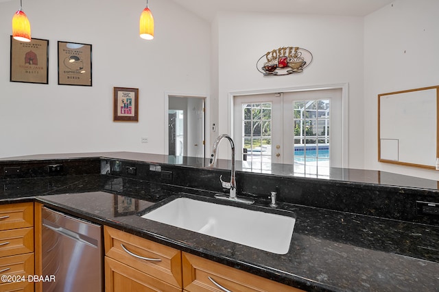 kitchen featuring dark stone countertops, pendant lighting, lofted ceiling, and sink