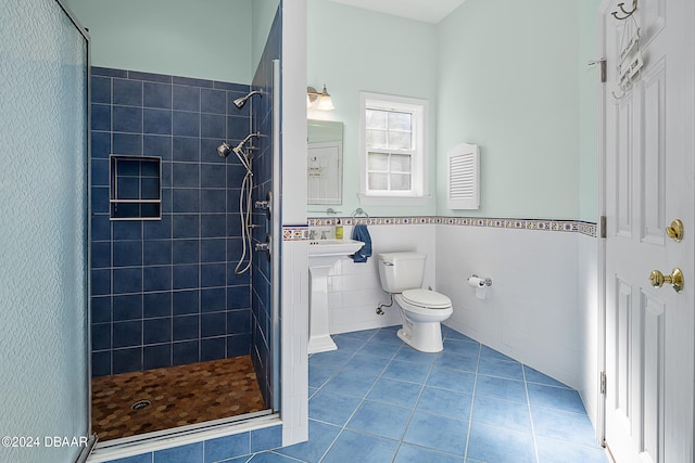 bathroom featuring tile walls, tile patterned floors, toilet, and a tile shower