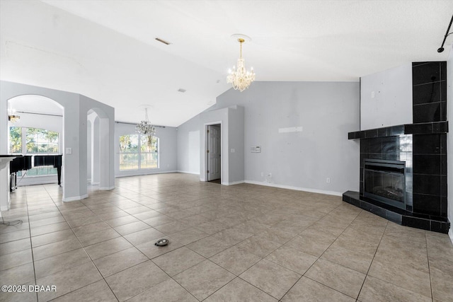 unfurnished living room featuring light tile patterned floors, lofted ceiling, a tile fireplace, and an inviting chandelier