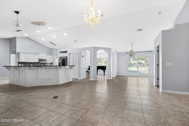 kitchen featuring a kitchen bar, backsplash, stainless steel appliances, white cabinetry, and light tile patterned flooring