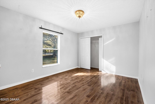 unfurnished bedroom featuring a textured ceiling, dark wood-type flooring, and a closet