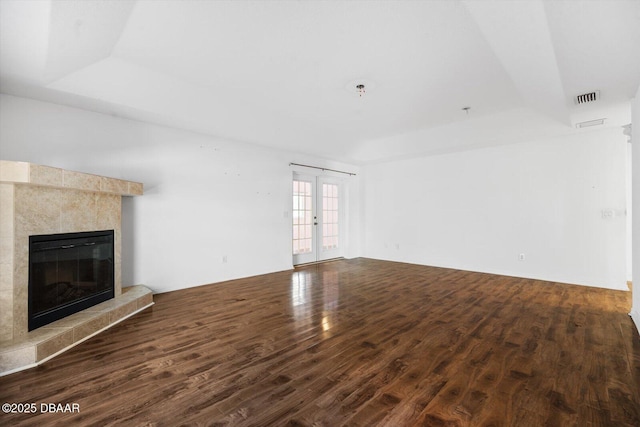 unfurnished living room featuring dark hardwood / wood-style flooring, french doors, a tile fireplace, and a tray ceiling