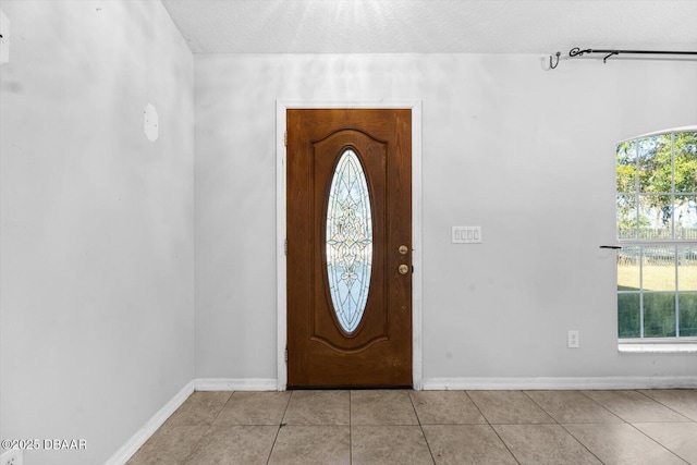 foyer with plenty of natural light, light tile patterned floors, and a textured ceiling