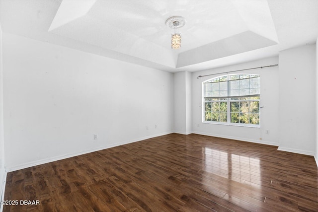 spare room with dark hardwood / wood-style flooring and a tray ceiling