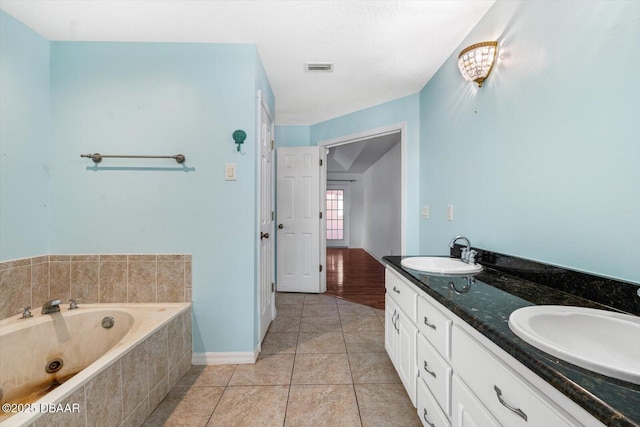 bathroom with tile patterned flooring, vanity, and a relaxing tiled tub