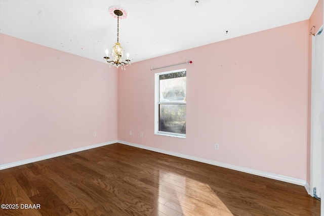 spare room featuring wood-type flooring and an inviting chandelier