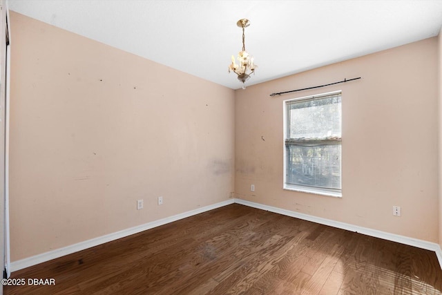 unfurnished room with wood-type flooring and an inviting chandelier