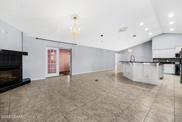 unfurnished living room with light tile patterned floors, sink, vaulted ceiling, and a tiled fireplace