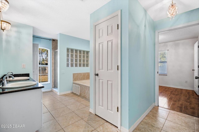 bathroom with tile patterned floors, a textured ceiling, vanity, independent shower and bath, and a notable chandelier