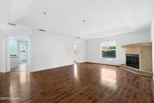 unfurnished living room featuring hardwood / wood-style floors, a raised ceiling, and a tiled fireplace