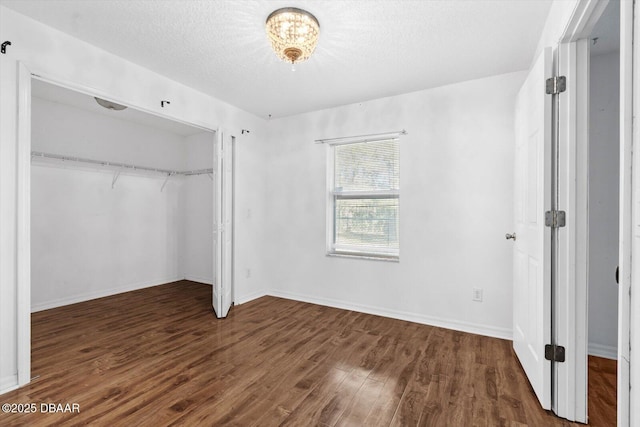 unfurnished bedroom with a textured ceiling, dark hardwood / wood-style flooring, and a closet