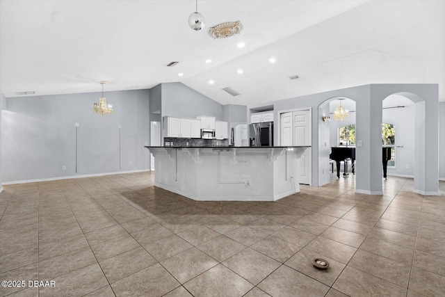 kitchen with decorative backsplash, appliances with stainless steel finishes, a kitchen breakfast bar, pendant lighting, and white cabinetry