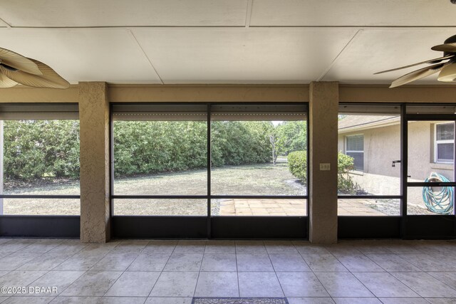 unfurnished sunroom featuring a ceiling fan and a wealth of natural light