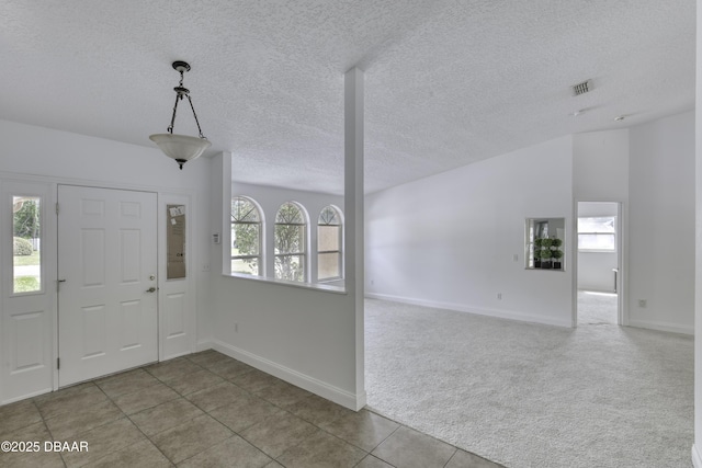 tiled foyer entrance featuring baseboards, carpet floors, and a textured ceiling