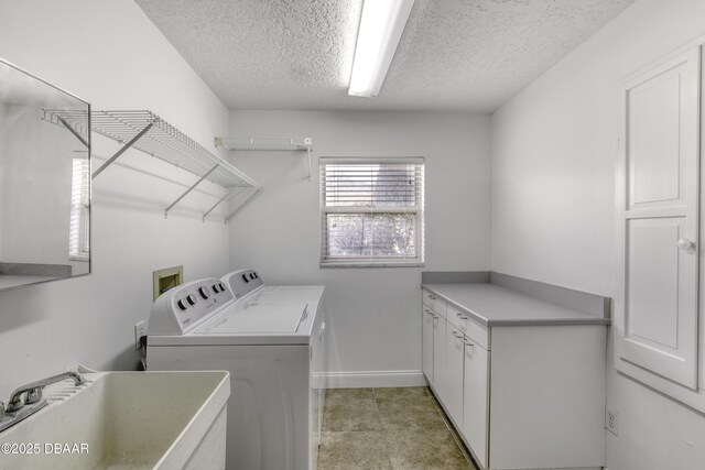 laundry room featuring cabinet space, a sink, a textured ceiling, baseboards, and washing machine and dryer