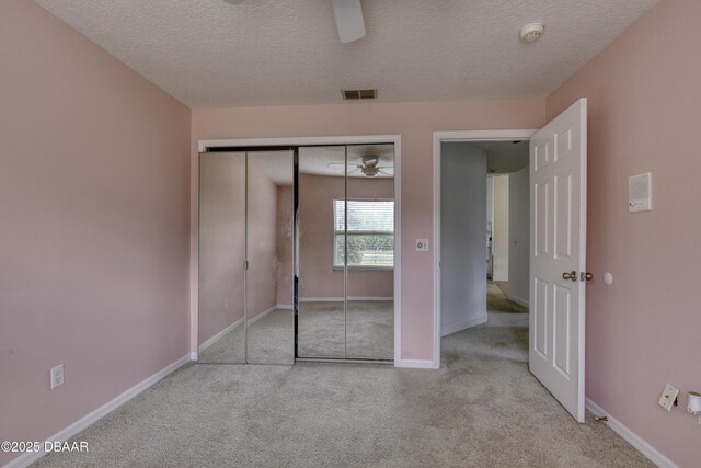 unfurnished bedroom with carpet floors, a textured ceiling, visible vents, and baseboards