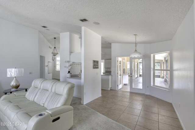 living room featuring visible vents, a textured ceiling, lofted ceiling, and a healthy amount of sunlight