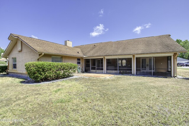 rear view of house with a yard, a chimney, and a sunroom