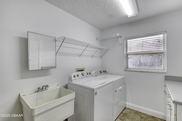 laundry room with independent washer and dryer, cabinet space, a sink, a textured ceiling, and baseboards
