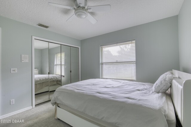 bedroom featuring carpet flooring, a textured ceiling, baseboards, visible vents, and a closet