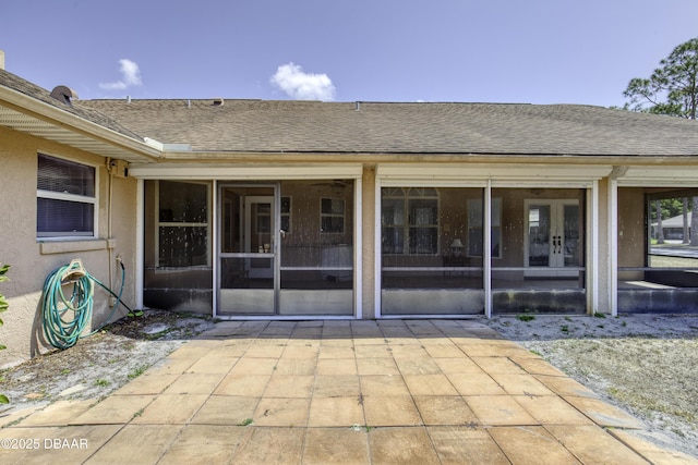 rear view of house with roof with shingles, a patio area, and a sunroom