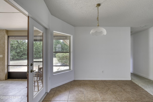 unfurnished dining area featuring french doors, a textured ceiling, light tile patterned floors, and baseboards