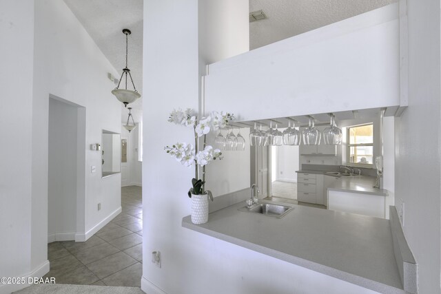 hallway with a sink, tile patterned floors, baseboards, and high vaulted ceiling