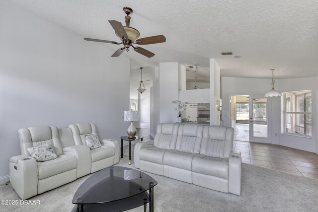 living room with visible vents, ceiling fan, a textured ceiling, tile patterned floors, and carpet