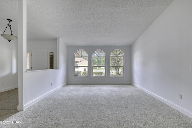 empty room featuring carpet floors, a textured ceiling, and baseboards