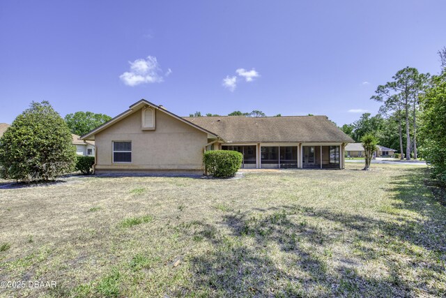 back of house with a sunroom, a lawn, and stucco siding