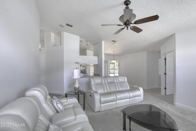 living area featuring visible vents, light carpet, baseboards, ceiling fan, and a textured ceiling