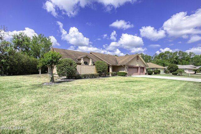 ranch-style home featuring concrete driveway, stucco siding, a front yard, and a garage