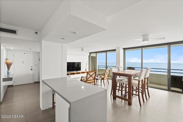 kitchen featuring kitchen peninsula, ceiling fan, light tile patterned flooring, white cabinetry, and a wall of windows