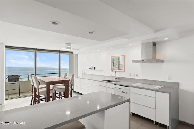 kitchen with a water view, wall chimney exhaust hood, sink, white cabinetry, and white appliances