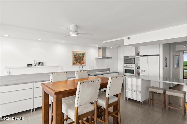 kitchen featuring appliances with stainless steel finishes, wall chimney exhaust hood, white cabinetry, and sink