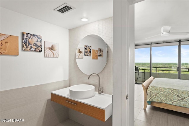 bathroom with tile patterned floors, tile walls, sink, floor to ceiling windows, and ceiling fan