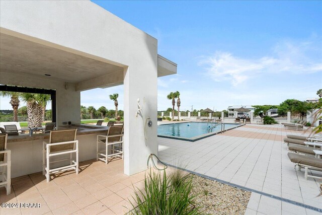 view of swimming pool with a patio area and a bar