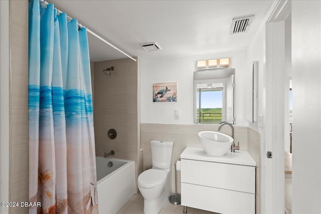 full bathroom featuring toilet, tile patterned floors, tile walls, vanity, and shower / bathtub combination with curtain