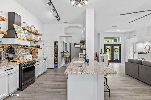 30 Bay Ct, Ormond Beach, FL 32174 - kitchen with range with electric stovetop, open shelves, open floor plan, a breakfast bar, and white cabinets