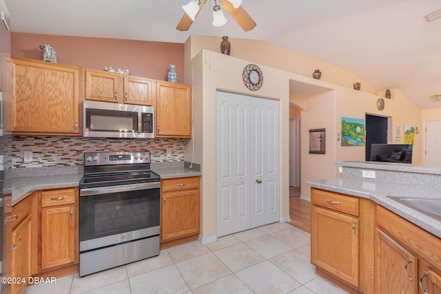 kitchen featuring ceiling fan, light tile patterned flooring, stainless steel appliances, and vaulted ceiling