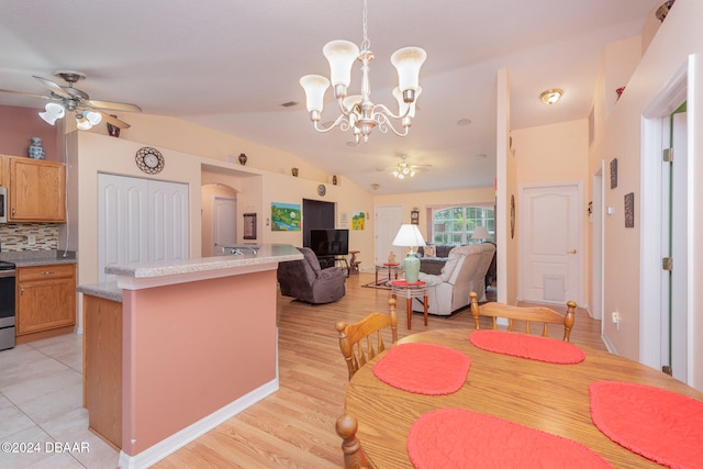 dining area featuring ceiling fan with notable chandelier, light wood-type flooring, and vaulted ceiling