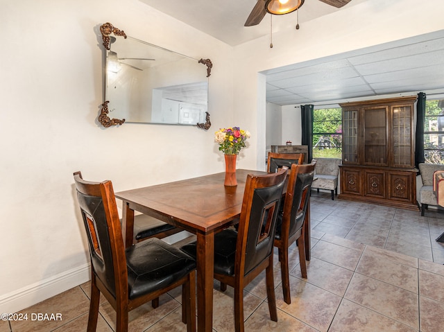 tiled dining room featuring a drop ceiling and ceiling fan