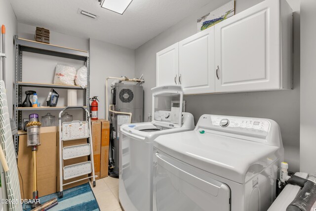 washroom featuring separate washer and dryer, electric water heater, cabinets, and light tile patterned flooring